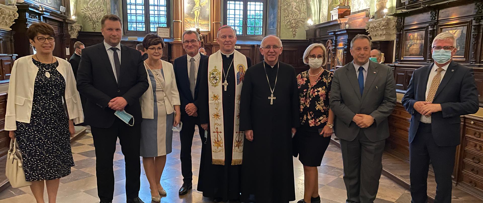 Minister Przemysław Czarnek w otoczeniu kuratorów oświaty i przedstawicieli władz kościelnych w zakrystii Sanktuarium Jasnej Górze. W tle malowidła na ścianach i bogato zdobione drewniane meble.