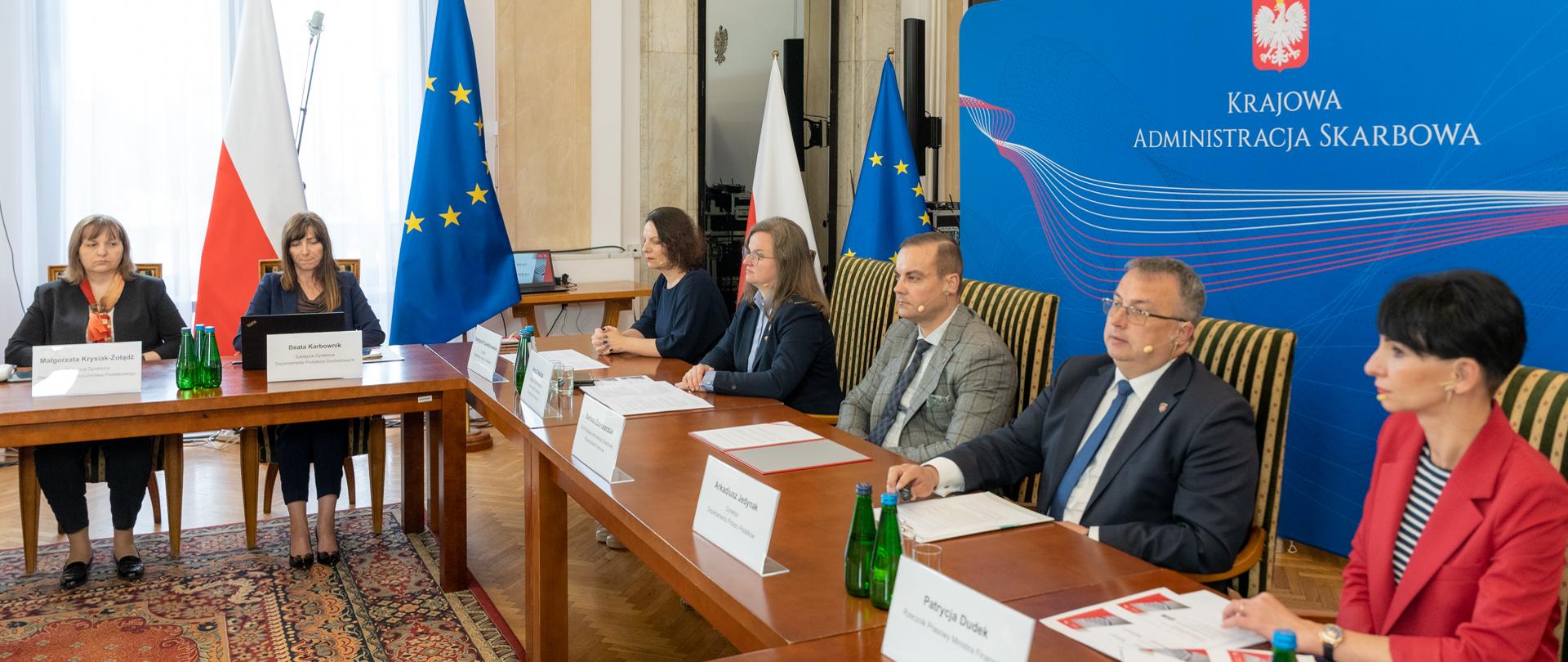 Uczestnicy spotkania, w tle ścianka z napisem Krajowa Administracja Skarbowa.