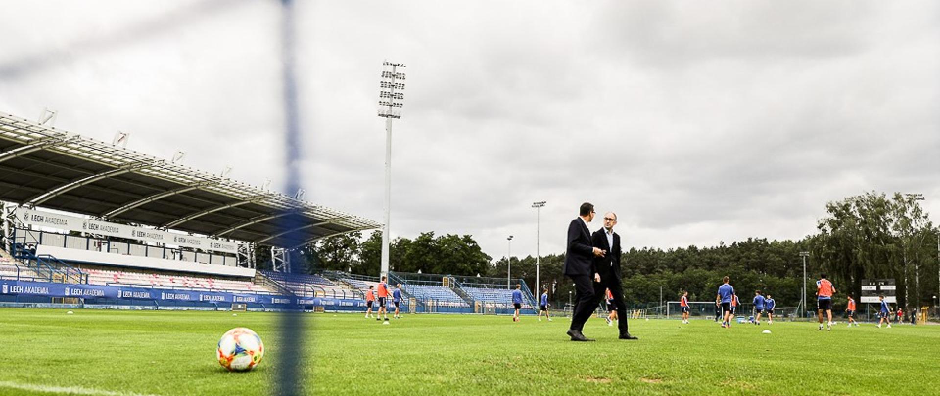 Premier Mateusz Morawiecki i prezes Lecha Poznań idą po murawie.