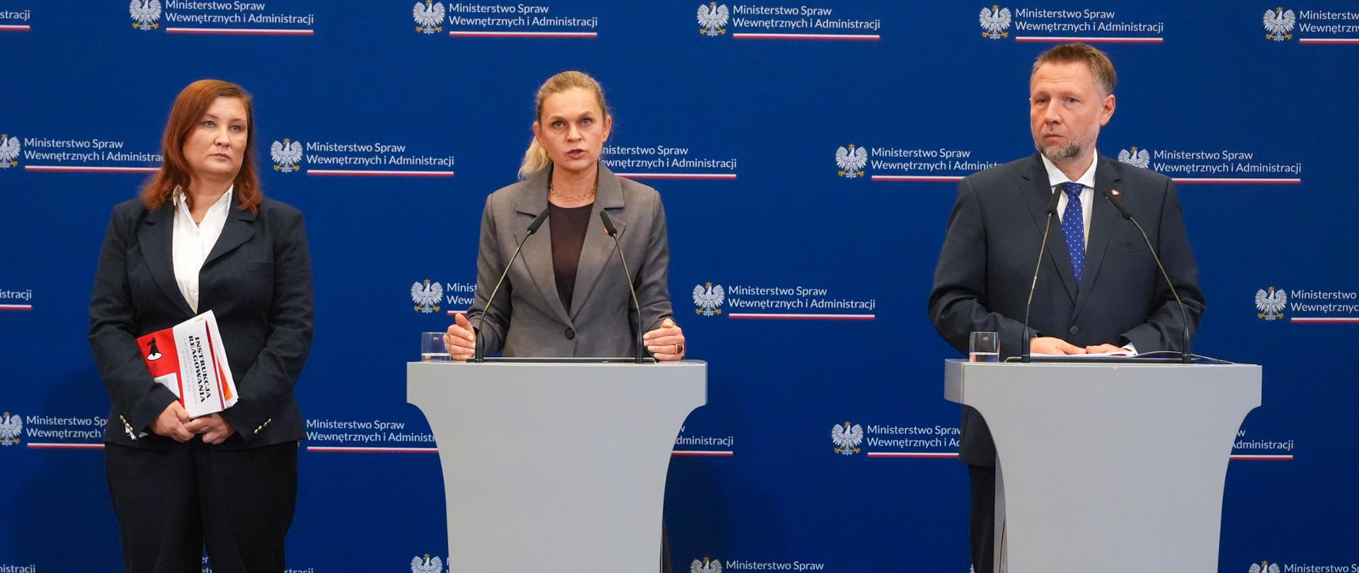 Ministra Edukacji Barbara Nowacka przemawia przy mównicy. Po jej lewej stronie stoi Podsekretarz Stanu Paulina Piechna-Więckiewicz, a po prawej Minister Spraw Wewnętrznych i Administracji Marcin Kierwiński na tle ścianki z logo MSWiA.