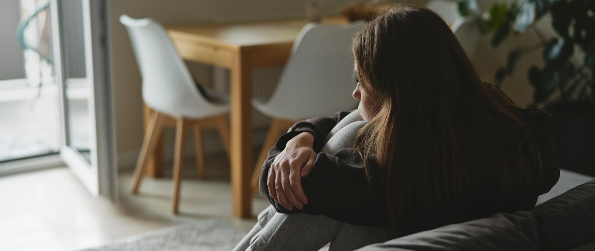 Caucasian sad woman sitting at the sofa with depression