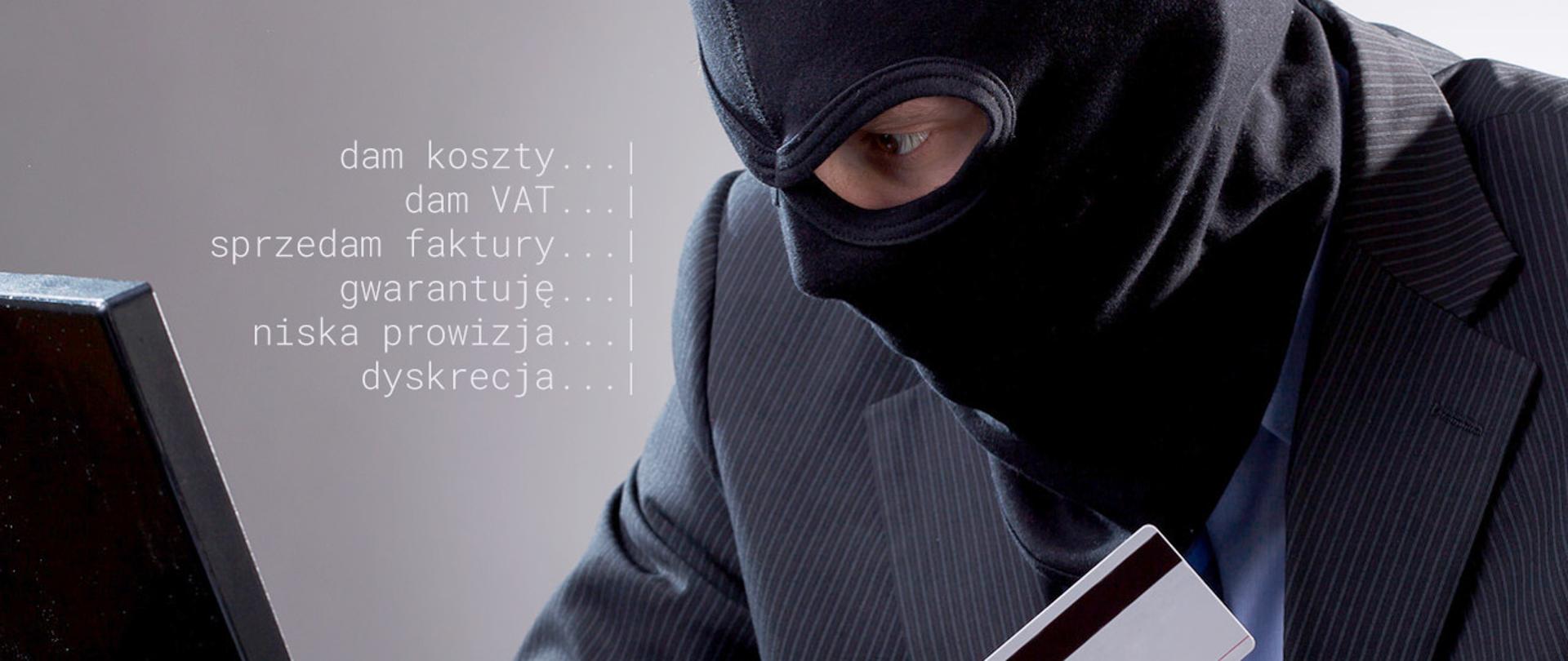 Zamaskowany mężczyzna przy laptopie patrzy w ekran