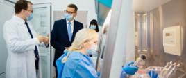 Premier rozmawia z lekarzem w laboratorium.