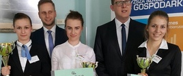  Trzy zwyciężczynie z dyplomami i pucharami. Z tyłu dwaj panowie