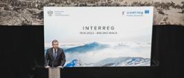 Widok na salę konferencyjną z góry, na scenie przy mównicy stoi minister Grzegorz Puda, przemawia do uczestników wydarzenia