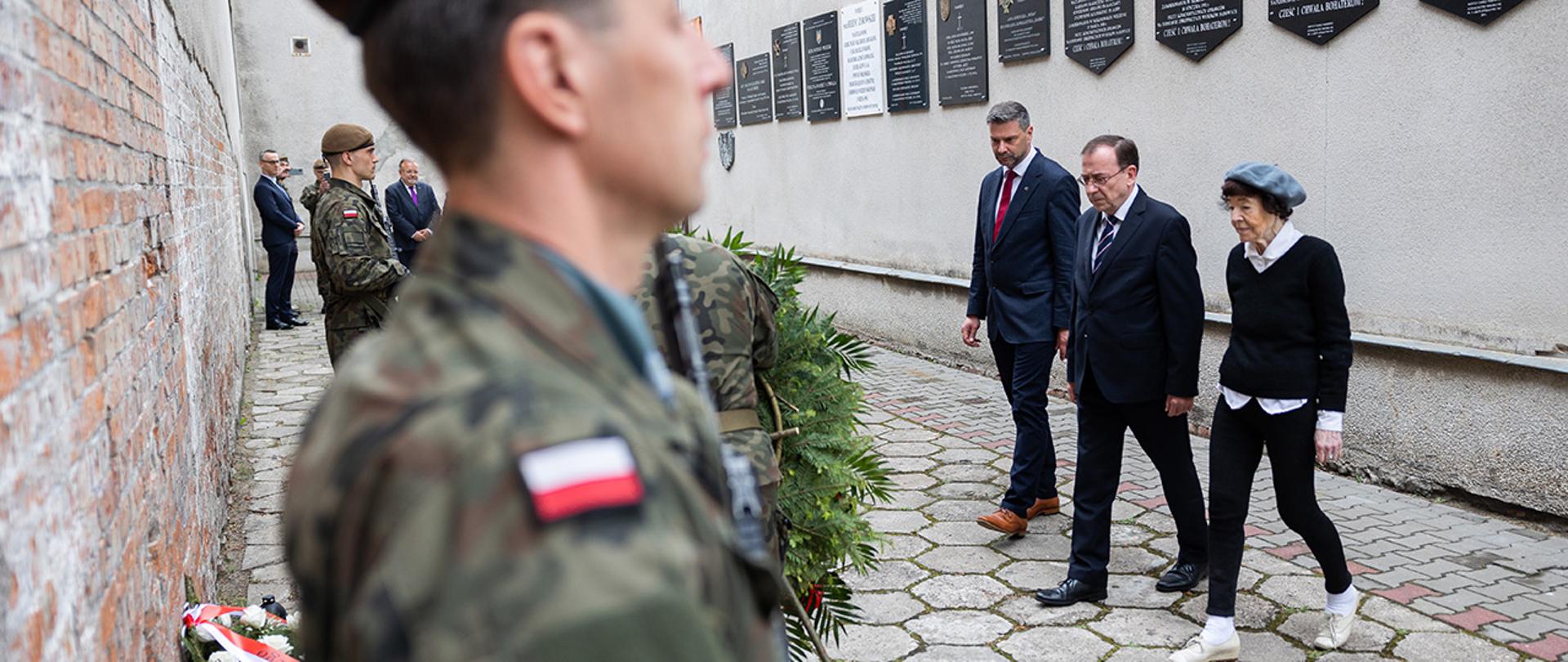 Na zdjęciu widać jak minister Mariusz Kamiński i Zofia Pielecka-Optułowicz składają wieniec przed ściana straceń.