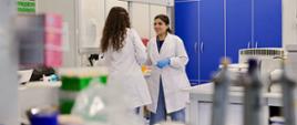 Dwie młode kobiety w fartuchach stoją w laboratorium 