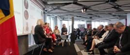na scenie siedzą paneliści, przed sceną uczestnicy konferencji