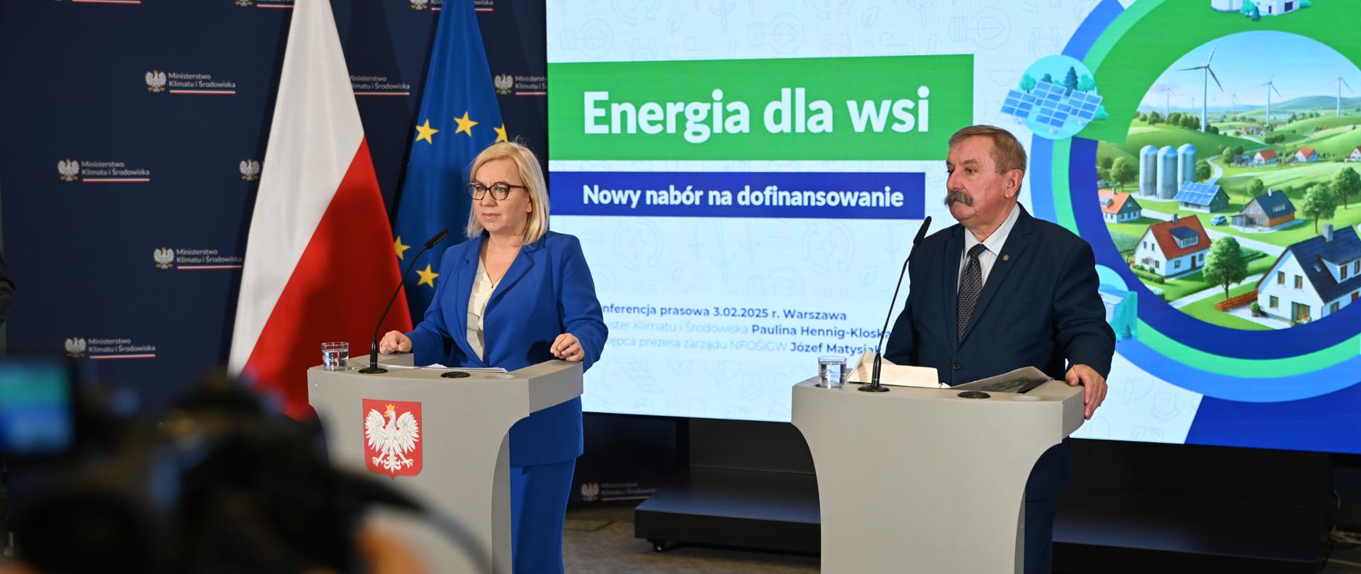 Konferencja ministry klimatu i środowiska Pauliny Hennig-Kloski oraz zastępcy prezesa zarządu NFOŚiGW Józefa Matysiaka, ogłoszenie II naboru wniosków "Energia dla wsi". Przedstawiciele obu instytucji stoją na tle telebimu z informacją o programie "Energia dla wsi" przed mównicami. Widać kamerę nagrywającą ich wystąpienie. 