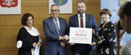 Minister Grzegorz Puda trzyma w dłoniach promesę 15 mln zł na dofinansowanie Szpitala Śląskiego w Cieszynie, po jego lewej stronie stoi wiceminister rodziny i polityki społecznej Stanisław Szwed
