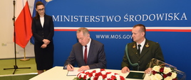 Minister środowiska Henryk Kowalczyk podpisuje nowy statut Polskiego Związku Łowieckiego w obecności wiceminister Małgorzaty Golińskiej i prezesa Prezydium Naczelnej Rady Łowieckiej Rafała Malca.
