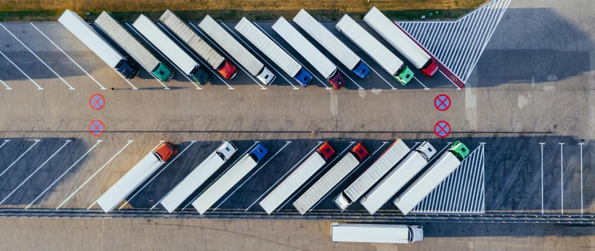 Kilka ciężarówek ustawionych bokiem do siebie na parkingu