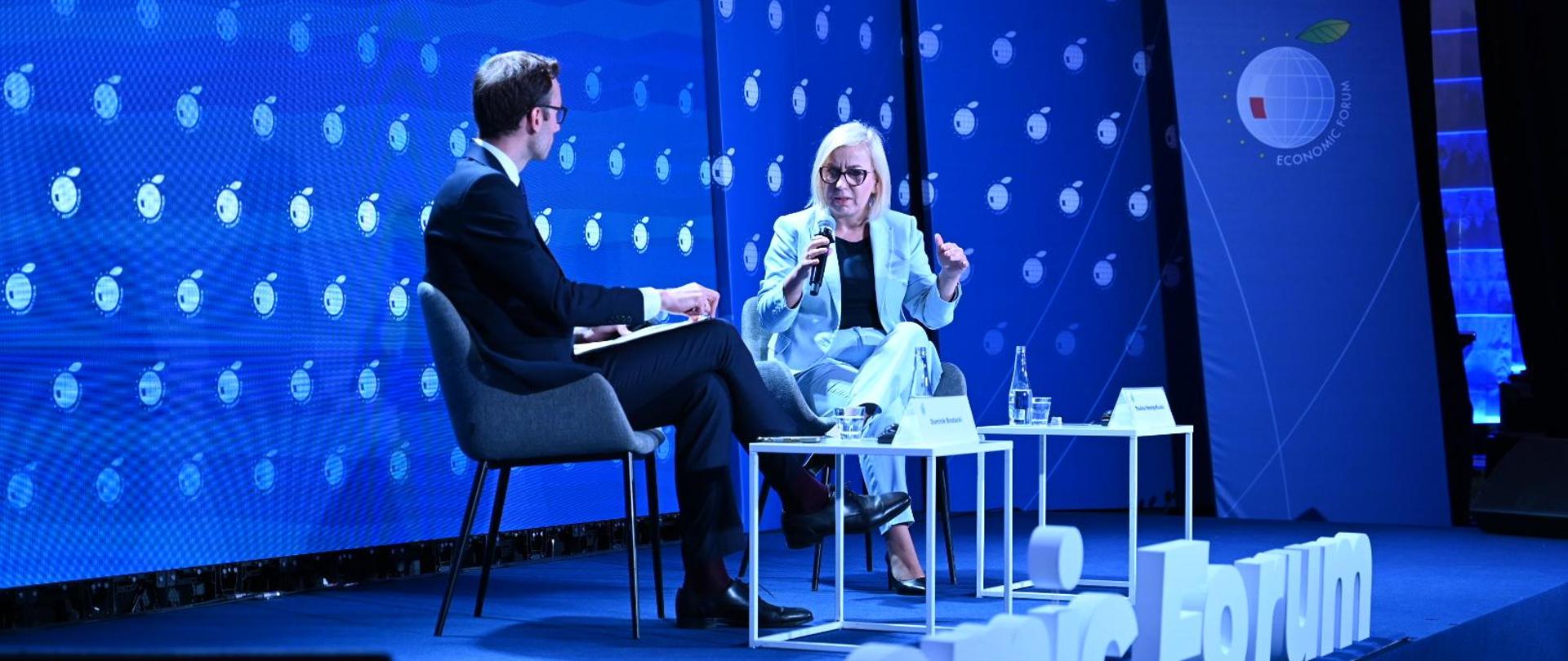 Ministra klimatu i środowiska Paulina Hennig-Kloska podczas XXXV Forum Ekonomicznego w Karpaczu. Na zdjęciu ministra siedzi na scenie i mówi do mikrofonu. Przed nią widać napis ,,Economic Forum"
