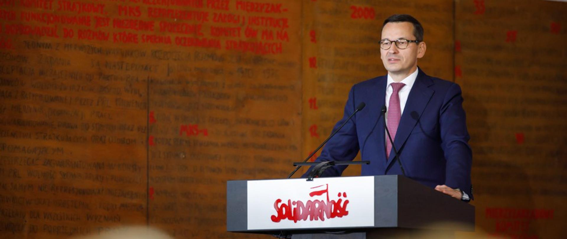 Premier przemawia na mównicy z napisem: Solidarność.