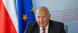 Minister Tadeusz Kościński na tle flagi UE i Polski 