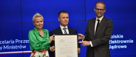 wiceminister Anna Łukaszewska-Trzeciakowska, prezes Mateusz Berger i wiceminister Adam Guibourgé-Czetwertyński prezentują pierwszą stronę decyzji środowiskowej