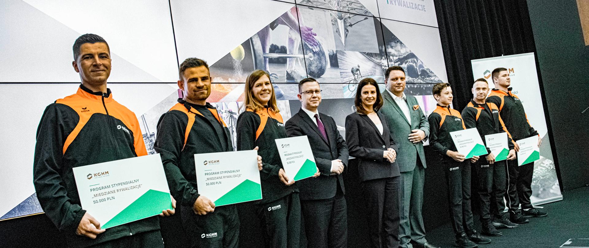 Grupowe zdjęcie uczestników konferencji wraz z Minister Sportu na scenie.