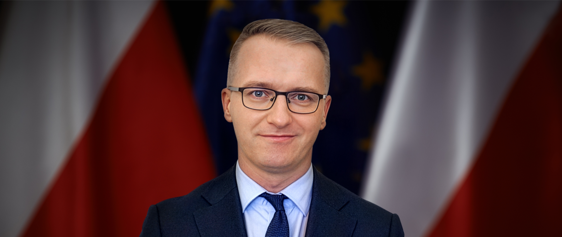 Dyrektor generalny MSiT Piotr Kudelski na tle flag polskiej i UE