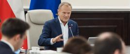 Premier Donald Tusk podczas posiedzenia Rady Ministrów 1.07.2025 r. Na zdjęciu widoczni Szef Kancelarii Prezesa Rady Ministrów, Minister Jan Grabiec oraz Minister Finansów Andrzej Domański. W tle flagi Polski i Unii Europejskiej.