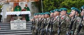 Na wyłożonym szarą kostką placu stoją w szeregach żołnierze w zielonych beretach, za nimi na podwyższeniu rozstawiony polowy ołtarz pod namiotowym daszkiem.