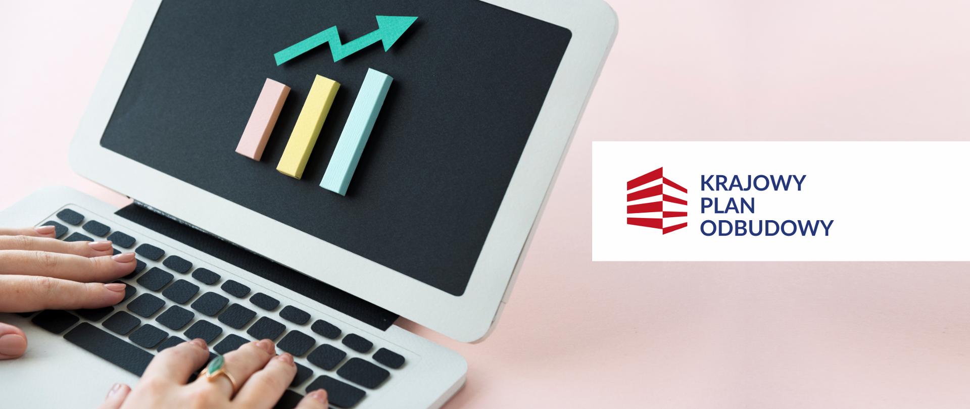 Laptop na bladoróżowy tle. Na czarnym ekranie laptop trzy słupki, nad nimi strzałka - pokazują wzrost. Na klawiaturze laptopa widoczne kobiece dłonie. Z prawej strony - logo Krajowego Planu Odbudowy.
