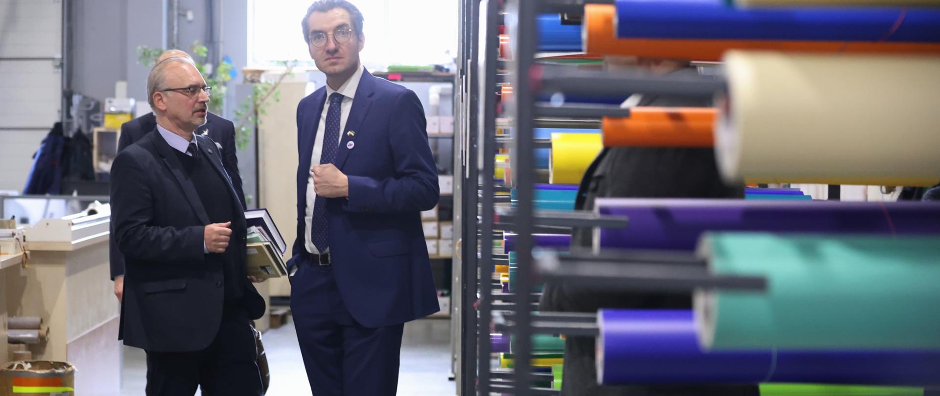 Dwie osoby stoją obok siebie w korytarzu w fabryce. Pierwszy od prawej stoi wiceminister Jan Szyszko.