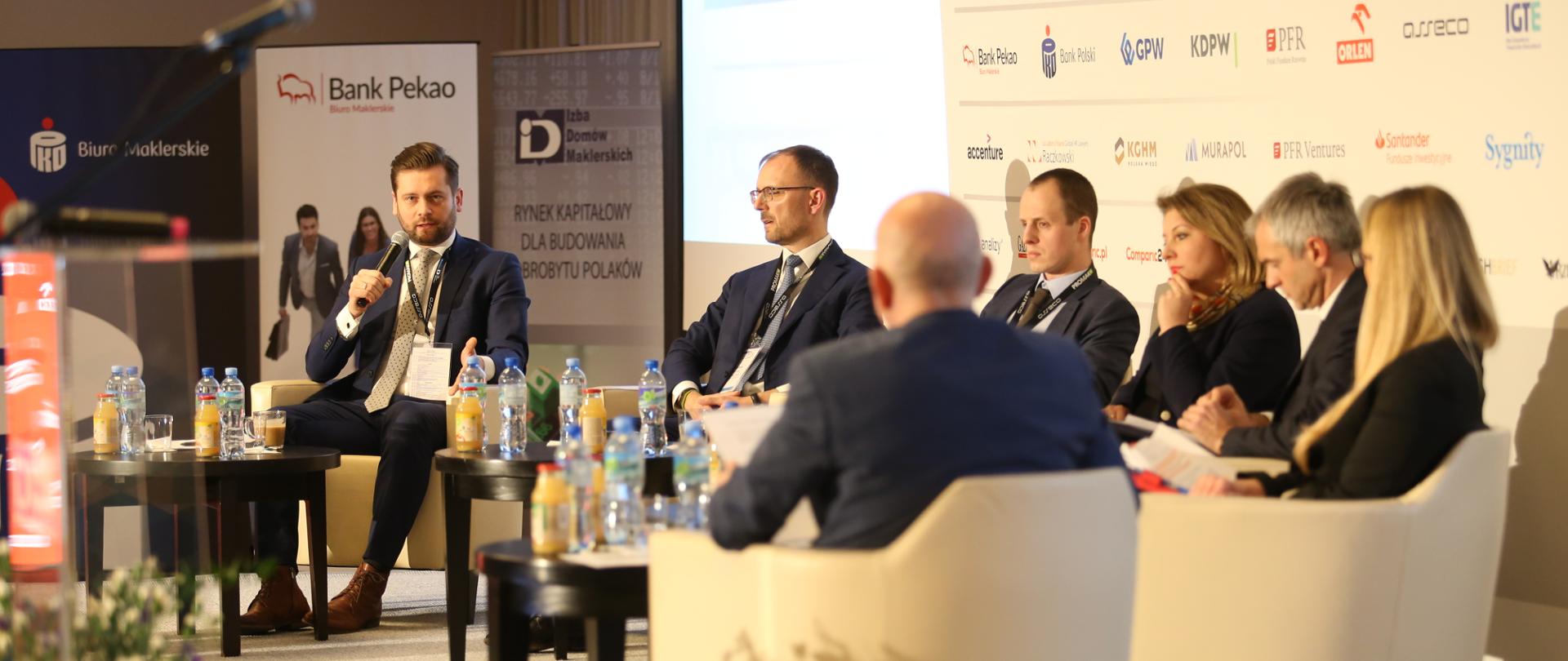 na fotelach siedzą uczestnicy panelu, do mikrofonu mówi wiceminister Kamil Bortniczuk