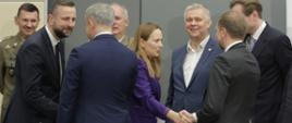 Grupa osób wita się ze sobą. 