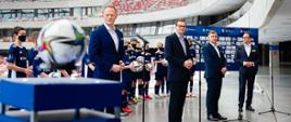 Od lewej: Olgierd Cieślik, Mateusz Morawiecki, Zbigniew Jagiełło i Marcin Animucki stoją podczas konferencji prasowej, w tle trybuny.