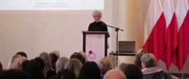 Iwona Michałek – wiceminister Edukacji Narodowej – przemawia na gali, w tle polskie flagi