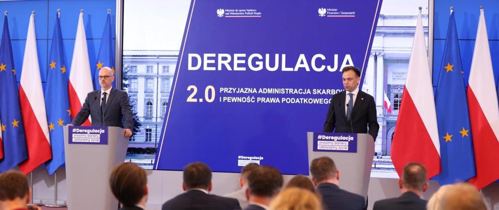 Dwie osoby stoją przy mównicach podczas konferencji prasowej poświęconej projektowi „Deregulacja 2.0”, a w tle widoczne są flagi Polski i Unii Europejskiej oraz ekran z nazwą wydarzenia.