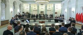 na zdjęciu uczestnicy debaty siedzą przy okrągłym stole