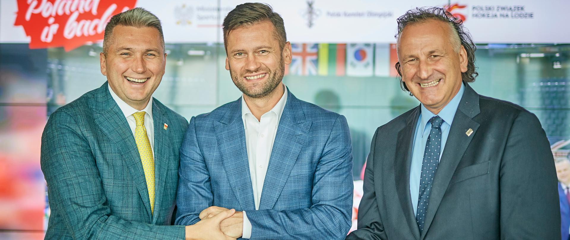 Minister Kamil Bortniczuk oraz prezes PKOL Radosław Piesiewicz i prezes Polskiego Związku Hokeja na Lodzie Mirosław Minkina ubrani w garnitury podają sobie ręce