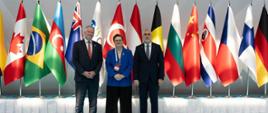 Wiceminister Katarzyna Lubnaer stoi pośrodku dwóch mężczyzn, przedstawicieli państw członkowskich szczytu Skills Summit 2026 w Stambule. W tle za nimi ustawione są flagi różnych państw.