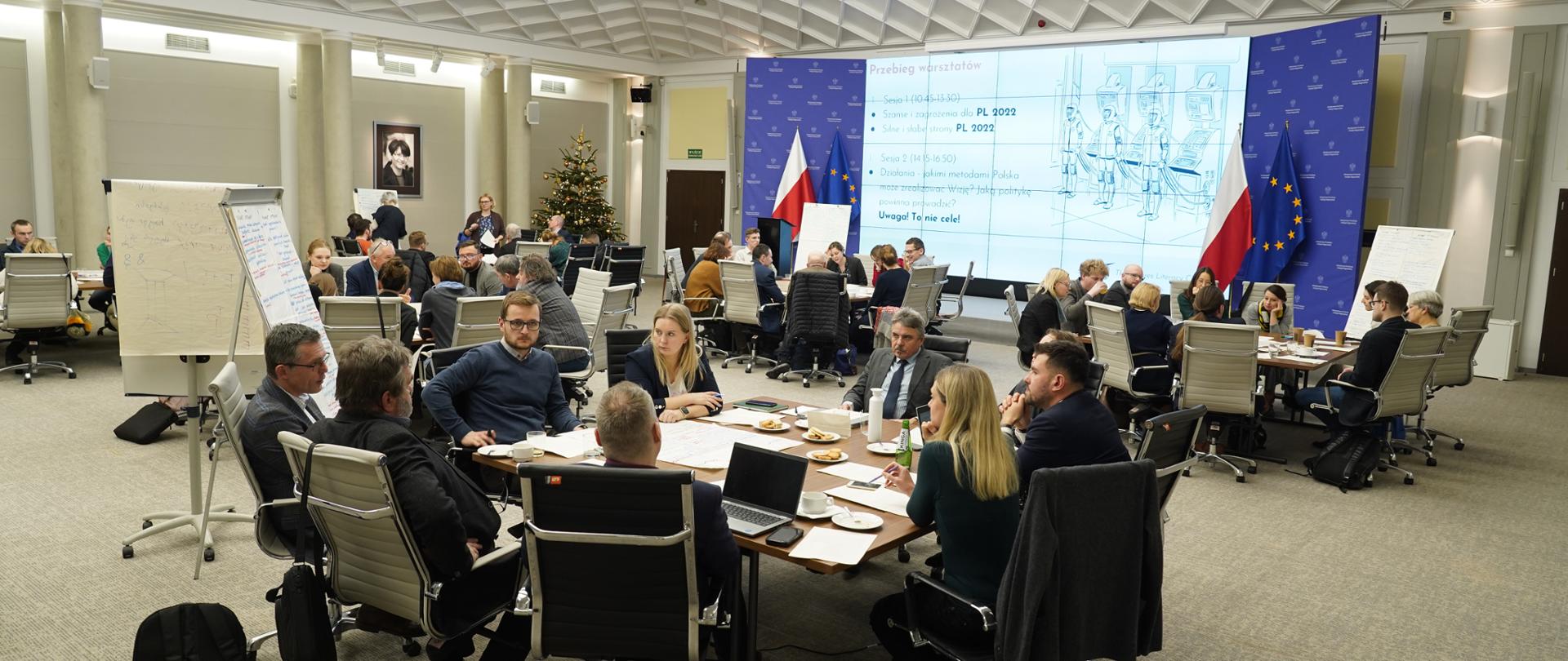 Przy trzech okrągłych stołach siedzą grupy ekspertów.