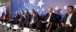 Minister funduszy i polityki regionalnej Grzegorz Puda przemawia podczas panelu dyskusyjnego na Forum w Karpaczu. Obok siedzą uczestnicy panelu.