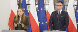 Minister funduszy i polityki regionalnej Katarzyna Pełczyńska-Nałęcz i marszałek Sejmu Szymon Hołownia stoją za mównicami z mikrofonami, za ich plecami flagi Polski i UE