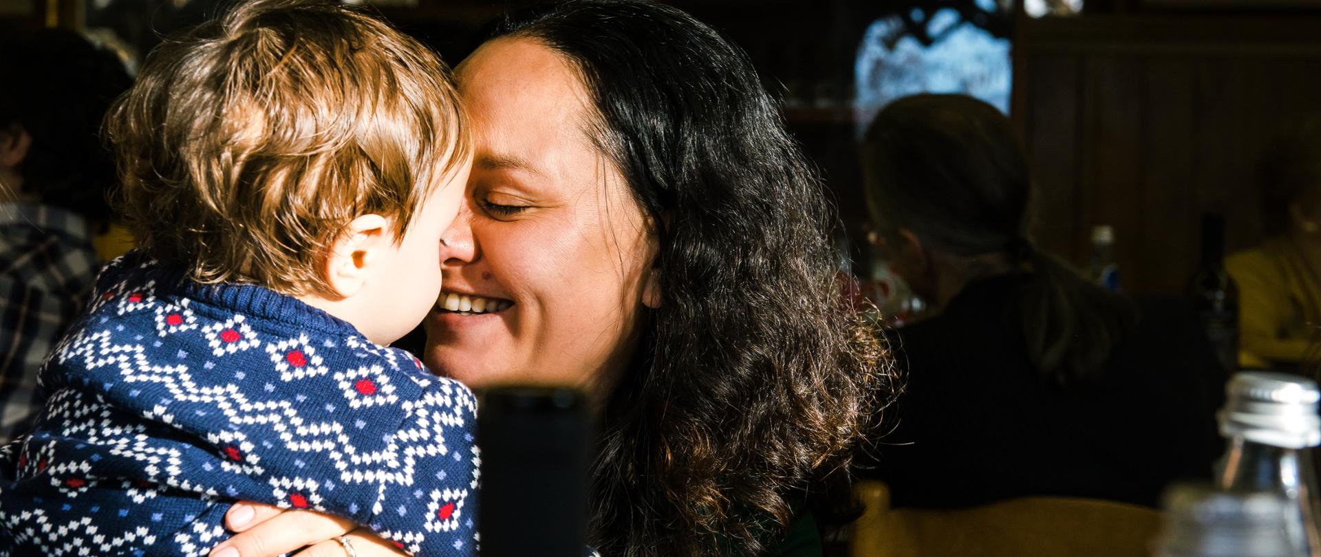 Mature woman face to face with baby son in cafe