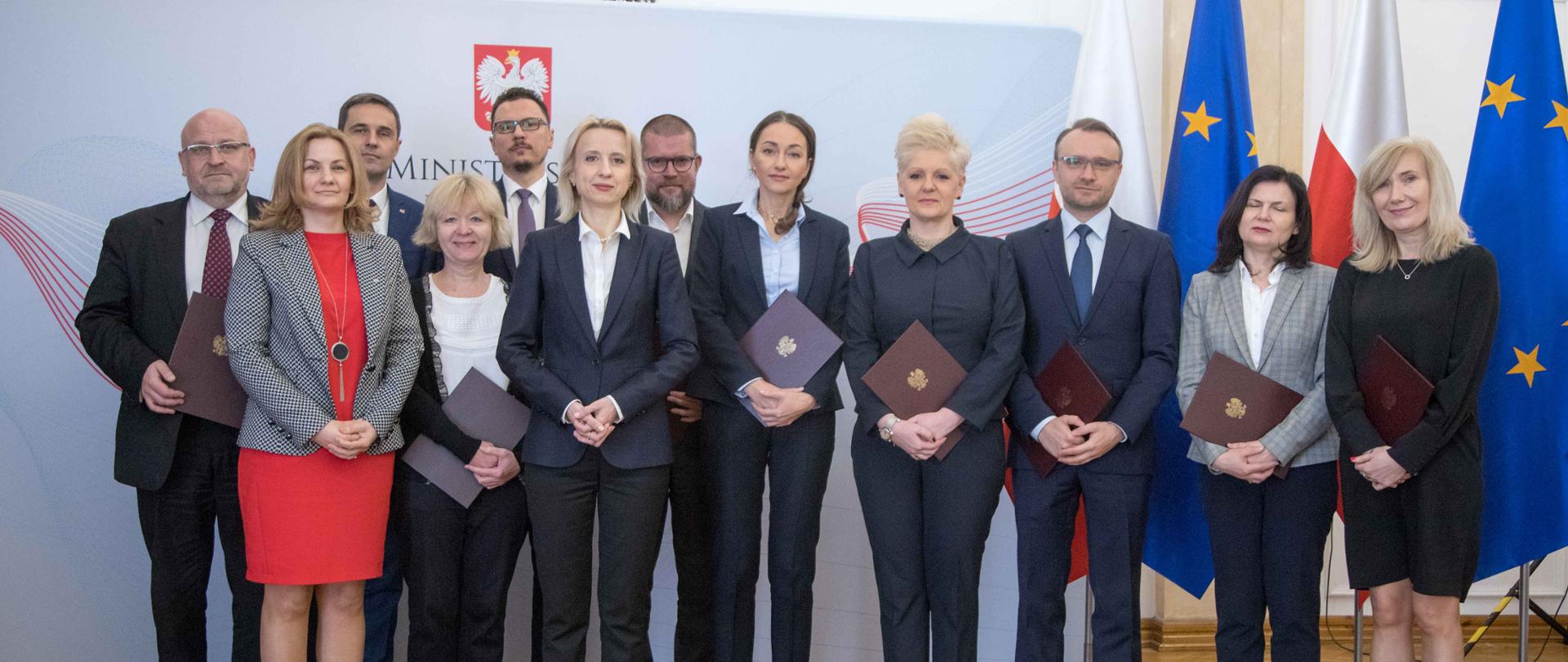 Członkowie Rady Edukacji Finansowej na tle baneru MF i flag