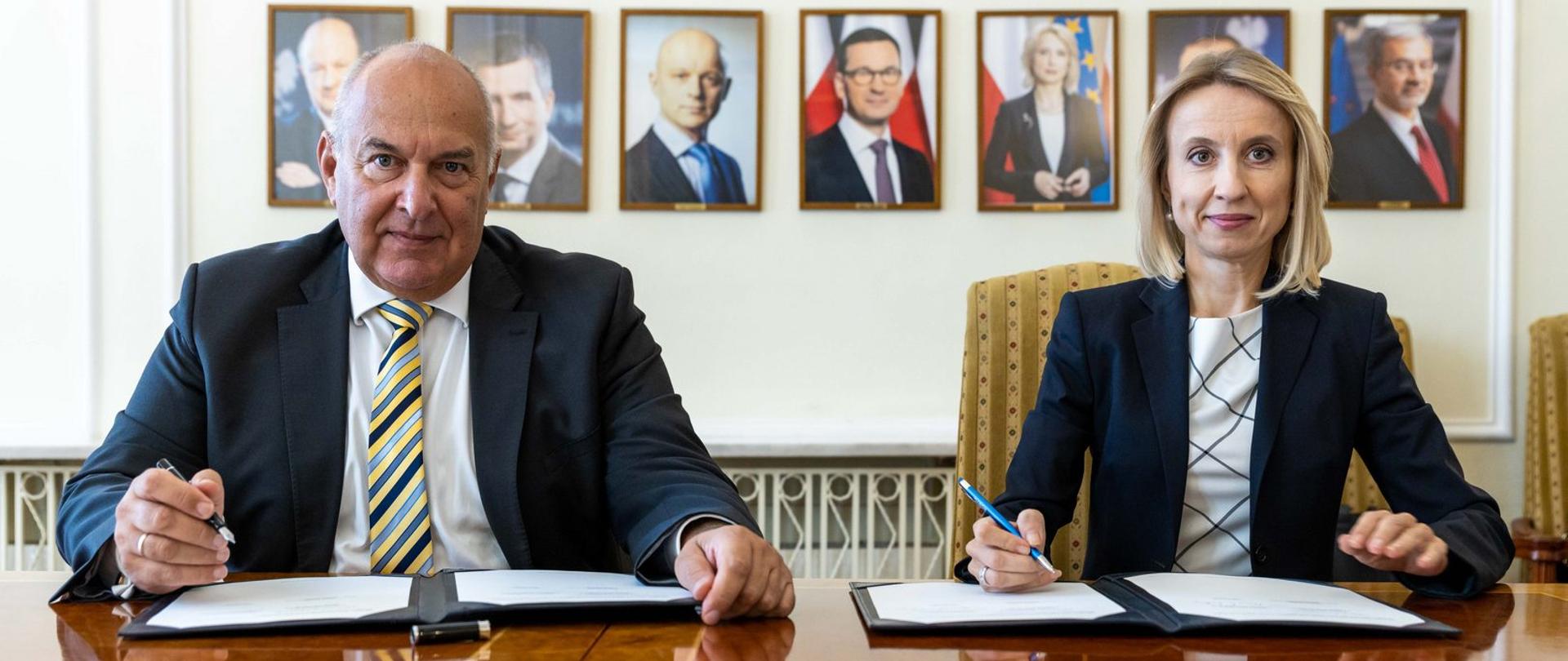 Minister Finansów Tadeusz Kościński i wiceprezes EBI Teresa Czerwińska na tle portretów byłych ministrów finansów