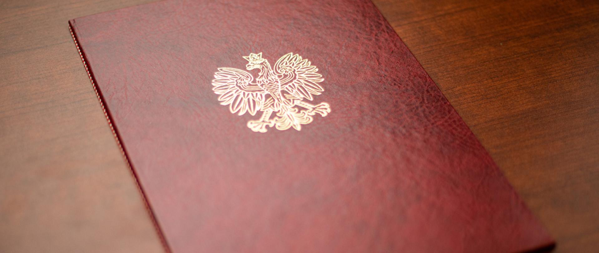 Na zdjęciu widać twardą oprawę na dokumenty z wytłoczonym orłem z godła narodowego.