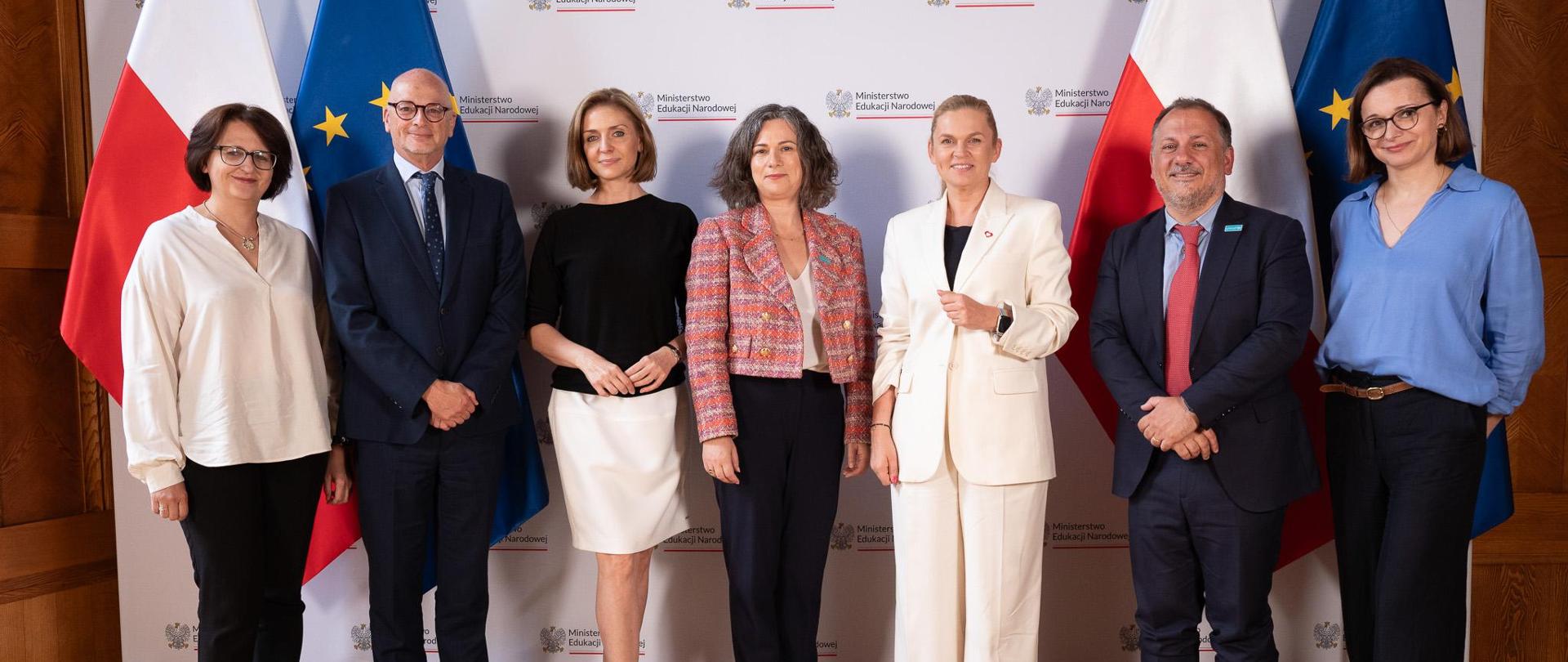 Spotkanie Minister Edukacji z Koordynator Krajową UNICEF na Polskę, Zdjęcie przedstawia wszystkich uczestników spotkania, którzy stoją na tle flag polski i unii europejskiej