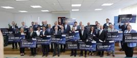 Beneficjenci podbeskidzkich gmin, które otrzymały dofinansowanie z 6. edycji Rządowego Programu Inwestycji Strategicznych, przedstawiciele gmin stoją i trzymają w dłoniach czeki