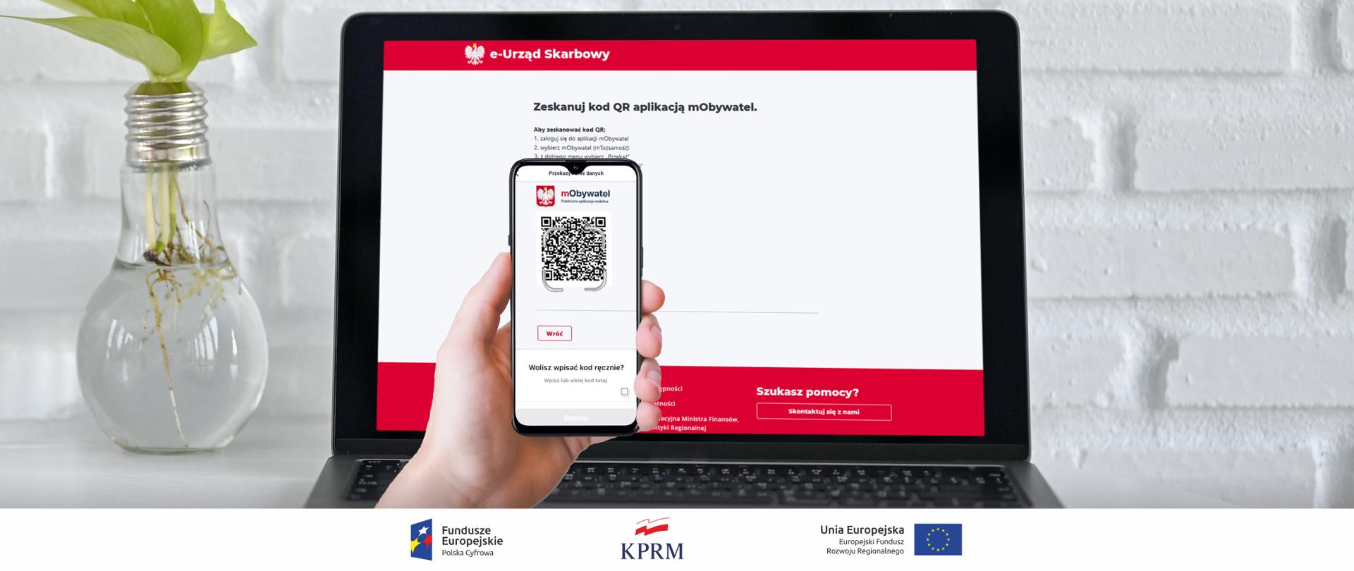 Laptop na ekranie strona logowania do usługi ePIT aplikacją mObywatel, przed ekranem ręka trzymająca smarfona - na ekranie aplikacja mObywatel z kodem QR umożliwiającym zalogowanie się do usługi ePIT.