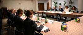 Spotkanie w sali konferencyjnej. Uczestnicy siedzą przy stołach naprzeciwko siebie. Na pierwszym planie jest delegacja polska, natomiast w tle - delegacja włoska.