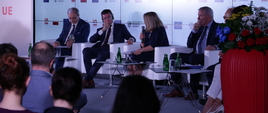 na scenie siedzą uczestnicy panelu, uczestnicy są zwróceniu w stronę sceny