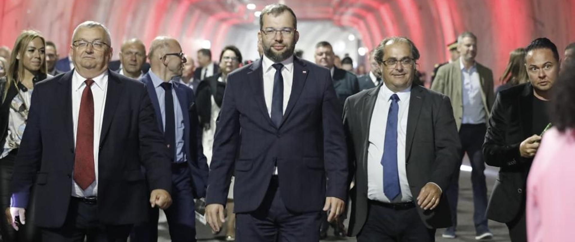Minister funduszy i polityki regionalnej Grzegorz Puda na otwarciu tunelu pod Świną, minister idzie drogą w tunelu, po jego lewej stronie minister infrastruktury Andrzej Adamczyk, po prawej wiceminister infrastruktury Marek Gróbarczyk 