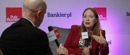 Minister funduszy i polityki regionalnej Katarzyna Pełczyńska-Nałęcz siedzi w fotelu i przemawia do mikrofonu, przed nią siedzi dziennikarz