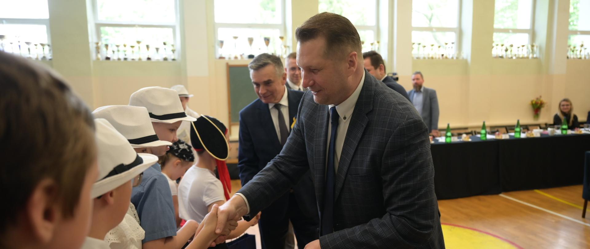Minister Czarnek ściska dłoń małemu dziecku.